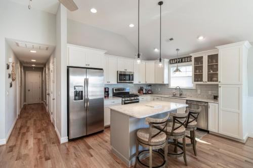 a kitchen with white cabinets and a island with bar stools at OBX Beach Gnome in Kill Devil Hills