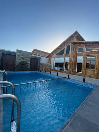 a large pool with blue water in front of a building at اكواخ السمو الريفيه in Khalij Salman