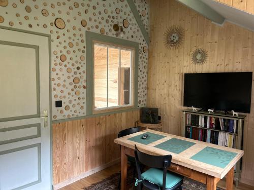 Cette chambre dispose d'une table, d'une télévision et d'une fenêtre. dans l'établissement Nature et Découvertes 1 ch, à Sirod