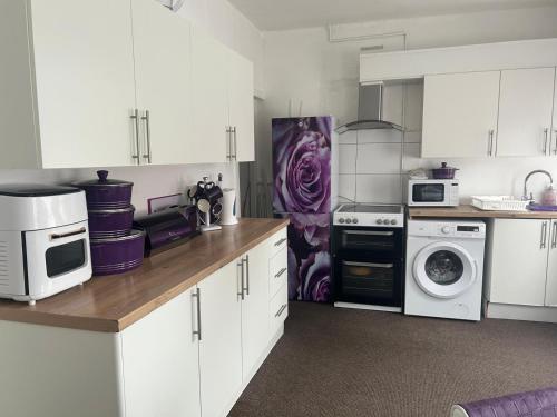 una cucina con mobili bianchi e un asciugamano viola di Skyline Self Service a Leigh