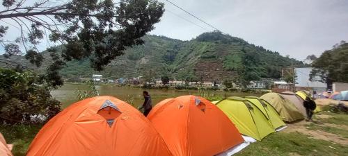 a group of tents parked next to a river at Sochech Camping Ground in Kejajar