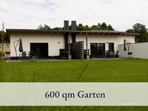 a white house with a lawn in front of it at Fewo River I Familienfreundlich I großer Garten I inkl Badefass I Kamin I Spielplatz in Wendisch Rietz