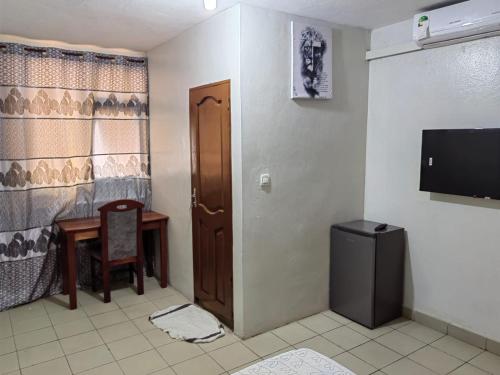 a room with a door and a table and a television at Tadagbe Appart in Cotonou