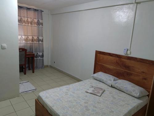 a bedroom with a bed with a wooden head board at Tadagbe Appart in Cotonou