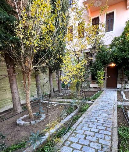 a stone walkway in front of a building with trees at Αρχοντικό Βιζυηνού in Xanthi