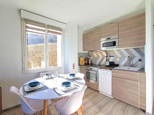 une cuisine avec une table blanche et des chaises dans l'établissement T3 au Pla d'Adet 1700m pour 6 pers, confort équipé - FR-1-457-355, à Saint-Lary-Soulan
