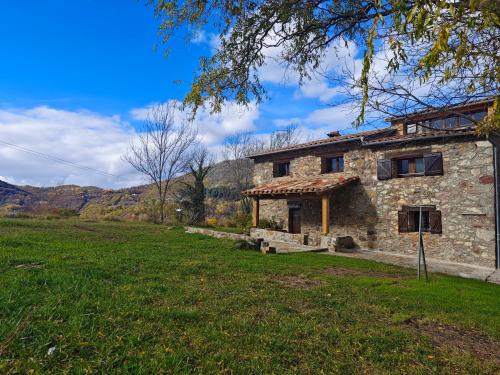 a stone house in a field next to a field at Can Tadeu in Camprodon