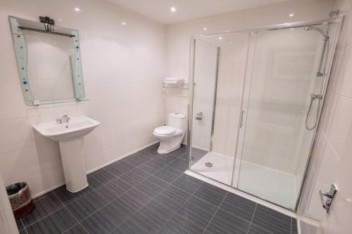 a bathroom with a shower and a toilet and a sink at Banks Hotel in Ilford