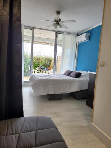 une chambre avec deux lits et un ventilateur de plafond dans l'établissement Vela Aurea, Studio 4 couchages en rez de jardin, avec terrasse et parking, à 500m de la plage, au Grau-du-Roi