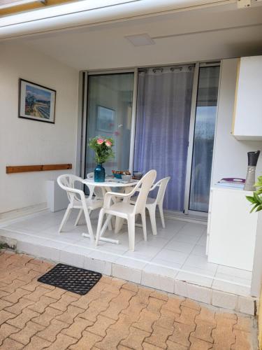 un patio avec une table et des chaises sur un balcon dans l'établissement Vela Aurea, Studio 4 couchages en rez de jardin, avec terrasse et parking, à 500m de la plage, au Grau-du-Roi