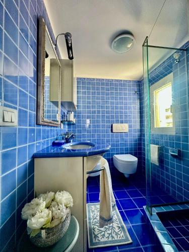 a blue tiled bathroom with a sink and a mirror at La Terrazza in Senigallia