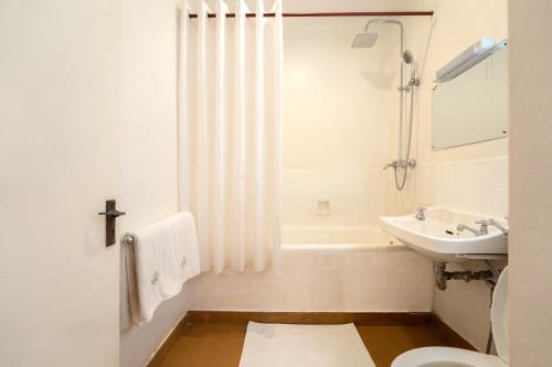 a bathroom with a sink and a tub and a toilet at Masindi Hotel in Masindi