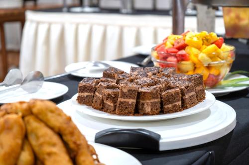 a table topped with plates of brownies and a bowl of fruit at Masindi Hotel in Masindi