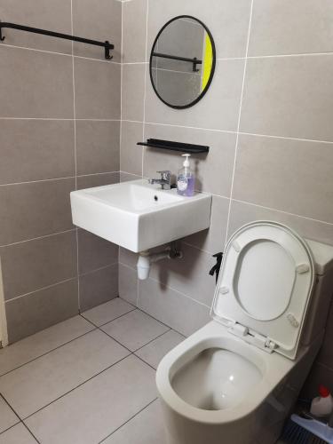 a bathroom with a toilet and a sink and a mirror at Homestay Medina Sendayan in Kampong Baharu Jimah