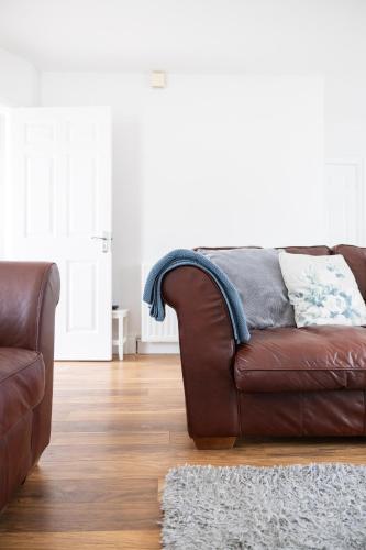 a brown leather couch in a living room with a rug at Beach Park House in Downings