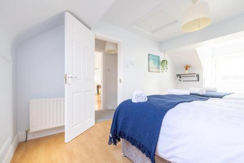 a white bedroom with a large bed with a blue blanket at Beach Park House in Downings