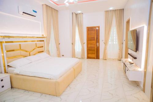 a white bedroom with a bed and a television at Home in Lekki in Lekki