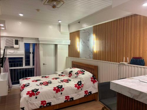 a bedroom with a bed with a white blanket with red flowers at Tagaytay Prime Residence City Land in Tagaytay