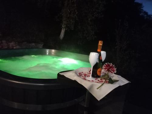 a hot tub with a bottle of wine on a table at PENSIUNEA DIMITRIOS Relaxare cu jacuzzi pe Valea Cernei in Băile Herculane