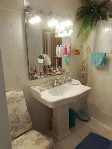 une salle de bain avec un lavabo, un miroir et une chaise dans l'établissement La Desirade, à Le Coudray-Macouard