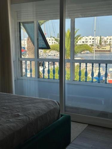 a bedroom with a view of a harbor through a window at Appartement luxe avec vue sur le port de Kantaoui in Port El Kantaoui