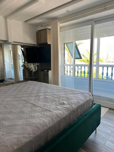 a bedroom with a large bed in a room with windows at Appartement luxe avec vue sur le port de Kantaoui in Port El Kantaoui