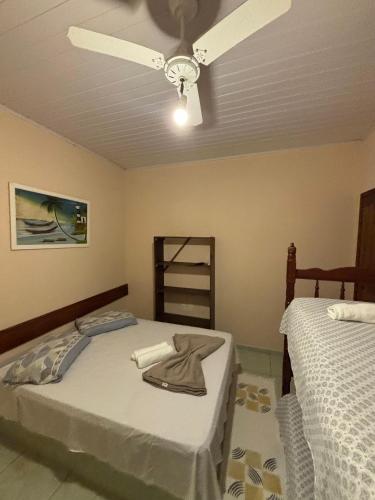 a bedroom with two beds and a ceiling fan at Pousada Tony Montana in Praia de Araçatiba