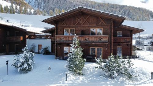 a log cabin in the snow with trees in front at Hotel & Chalets Edelweiss in Madonna
