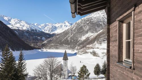 a view of a snowy mountain range with a church at Hotel & Chalets Edelweiss in Madonna