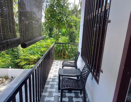 a balcony with two chairs and a table on a porch at Dalevista in Idukki