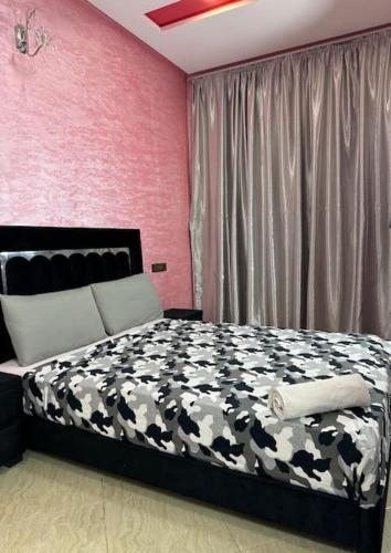 a bedroom with a black and white bed and pink walls at Appartement fes centre in Fès