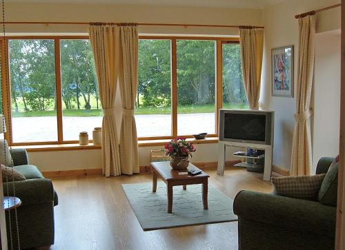 a living room with a large window and a tv at Plovermuir Cottage in Kirriemuir