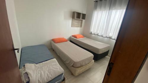 two beds in a small room with a window at Casa região central Guaratuba in Guaratuba