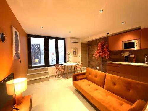 un salon avec un canapé et une cuisine avec une table dans l'établissement Bulle ocre, renové & climatisé dans le centre, à Nîmes