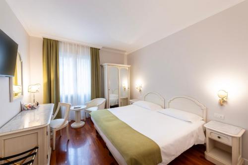 a hotel room with a large bed and a desk at Majestic Toscanelli (centro storico) in Padova
