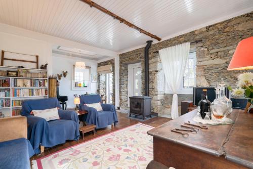 a living room with blue chairs and a stone wall at Casa da Fraga in Santa Marta de Penaguião