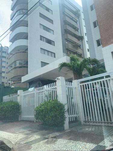 una recinzione bianca con una palma di fronte a un edificio di Apartamento lindo e perto da praia a Fortaleza