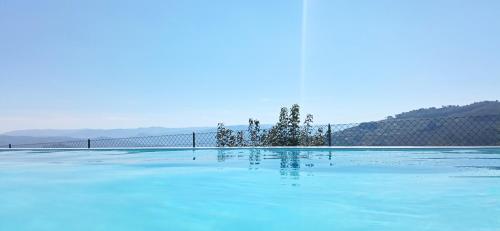 a swimming pool with blue water and trees in it at Casa da Fraga in Santa Marta de Penaguião