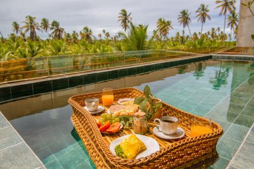 a table with food and drinks next to a swimming pool at Milagres Hospedagens - Praia e Vista Coqueiros in São Miguel dos Milagres