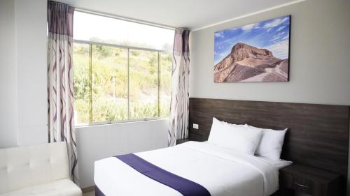 a bedroom with a bed and a large window at Hotel Gran Marquez in Moquegua