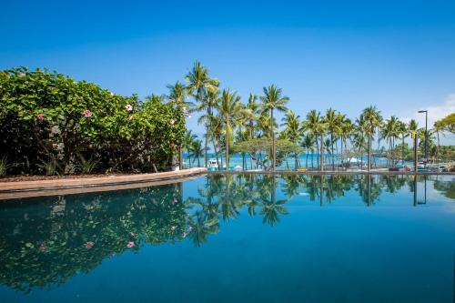 a swimming pool with palm trees and blue water at Kahalu'u Beach Villas 1-203 in Kailua-Kona