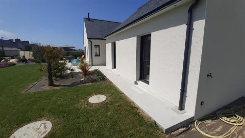 une maison blanche avec une pelouse à côté dans l'établissement Maison neuve à deux pas de la superbe plage des Amiets, à Cléder