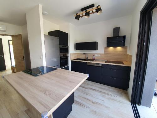 une cuisine avec des armoires noires et un comptoir en bois dans l'établissement Duplex neuf T3 terrasse et jardin proche plages, à Pietrosella