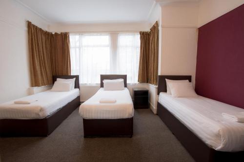 a hotel room with two beds and two lamps at Banks Hotel in Ilford
