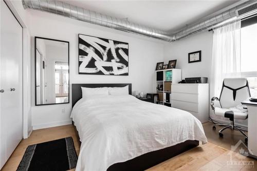 a bedroom with a large white bed and a chair at Vlad and Alex in Ottawa