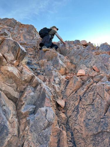 a man sitting on the side of a rocky mountain at Alt Duwisib Nature Escape in Duwisib