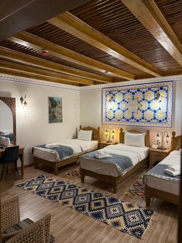 Habitación grande con 2 camas y mesa. en Mehrob Hotel Bukhara, en Bukhara