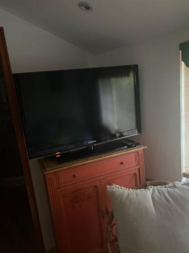 une grande télévision à écran plat sur une commode en bois dans l'établissement Le Mesnil Champêtre, à Ouville-la-Rivière