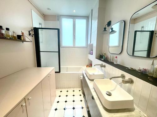 une salle de bain blanche avec un lavabo et un miroir dans l'établissement 3 bedrooms in Montmartre, à Paris