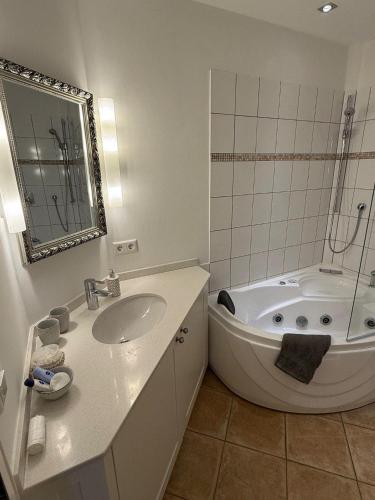 a white bathroom with a tub and a sink at Haus-Sonnenschein in Tinnum